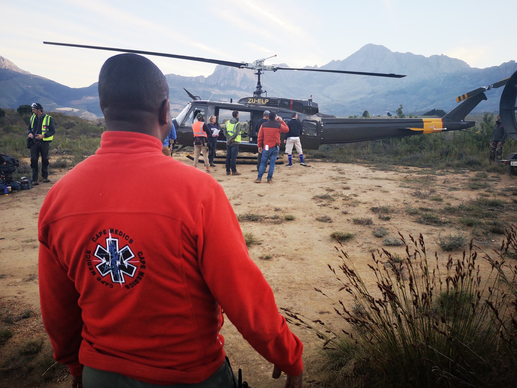 Cape Medics crew member overlooking a helicopter and crew at a mountain location