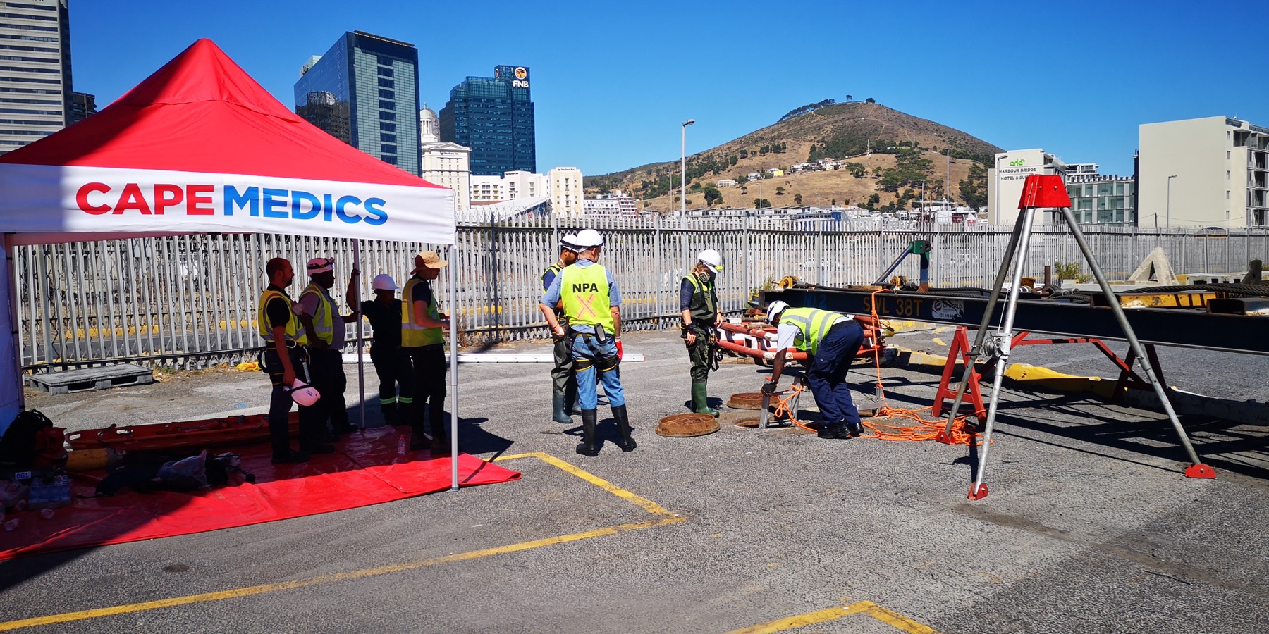 Rescue personnel preparing a stretcher and tripod beside a Cape Medics gazebo